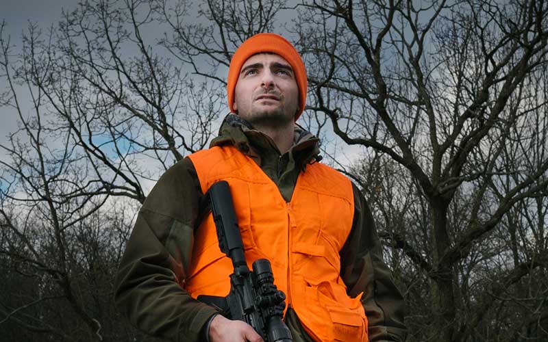 Hunter dressed in orange safety vest and hat