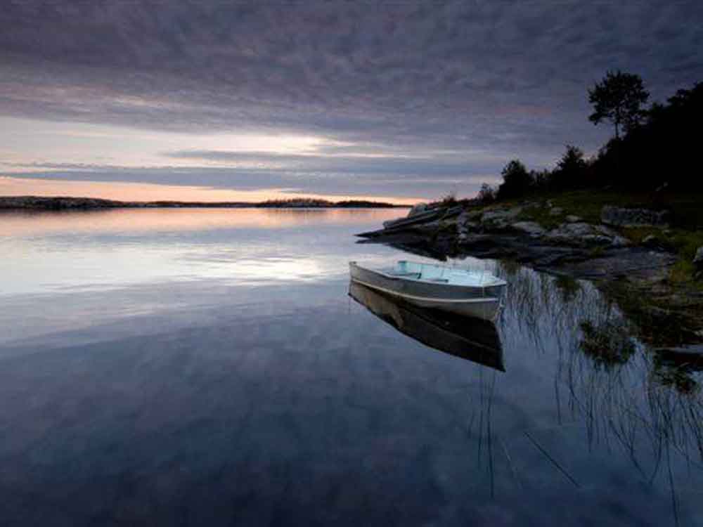 Boat at sunrise on calm Whiskeyjack Lake, Manitoba